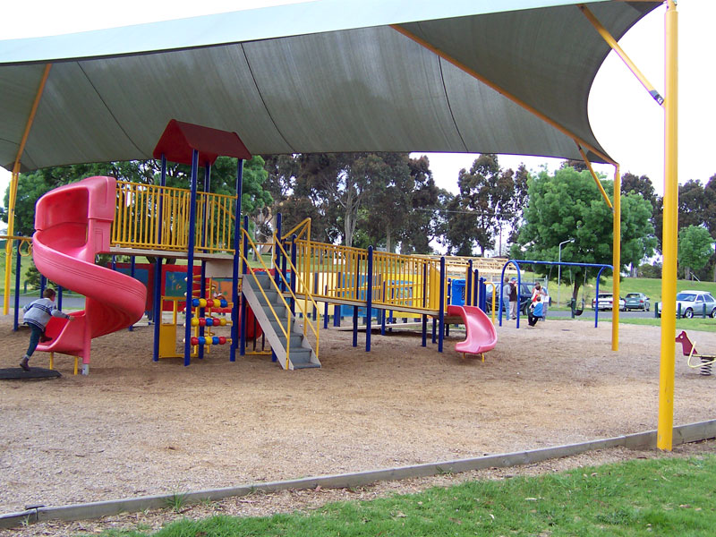 Playground with a red spiral slide under a shade sail