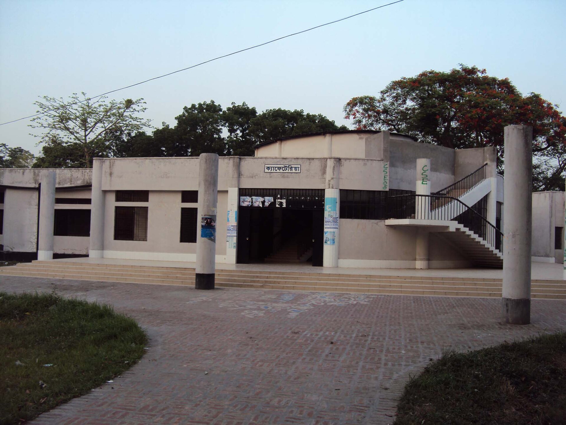 Low white cafeteria building with an outdoor stair and a sign in Bengali